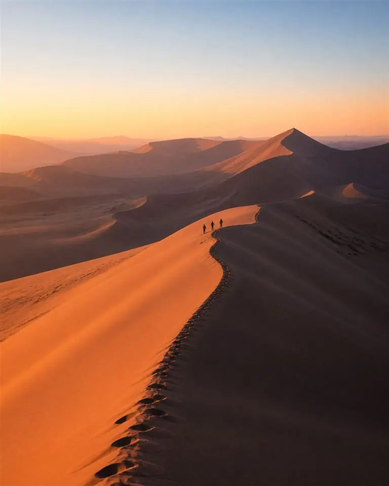 Dunes de Namibie au lever du soleil et marcheurs sur une crête